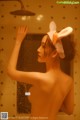 A naked woman with bunny ears on her head in the shower.