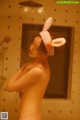 A naked woman in a bathtub with bunny ears on her head.