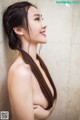 A woman with long brown hair standing in a bathroom.