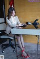 A woman sitting at a desk writing on a piece of paper.