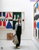 A woman standing in front of a painting in an art gallery.