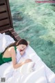 A woman in a green dress laying on a bed.