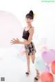 A young woman standing in front of a bunch of balloons.