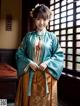 A woman in a blue and orange hanbok standing in front of a window.