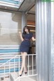 A woman in a blue dress standing on a stairwell.