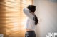 A woman standing in front of a window with blinds.