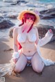 A woman in a white bikini sitting on a beach.