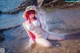 A woman in a white bikini sitting on the beach.