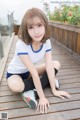 A young woman sitting on a wooden deck with her legs crossed.