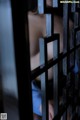 A woman is seen through the bars of a jail cell.