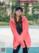 A woman standing on a basketball court wearing a pink hoodie.