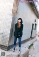 a woman standing in front of a building wearing a black hoodie