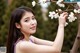 A woman in a purple dress holding a branch of a tree.