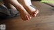 A person sitting on a wooden floor with their feet up.