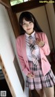 A woman in a pink blazer and plaid skirt posing for a picture.