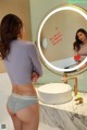 A woman standing in front of a mirror in a bathroom.