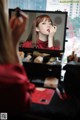 A woman applying lipstick in front of a mirror.