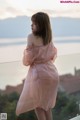 A woman in a pink dress standing on a balcony.