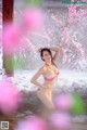 A woman in a pink bikini standing in the snow.