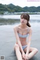 A woman in a bikini sitting on the beach.