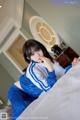 A woman in a blue and white outfit sitting on a bed.