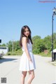 A woman in a white dress standing on a street.