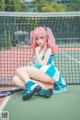 A woman with pink hair sitting on a tennis court.